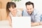 Heterosexual couple looking at a laptop smiling